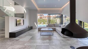 Una sala de estar moderna con un ventanal grande, un sof á, una mesa de centro y un televisor montado en la pared.