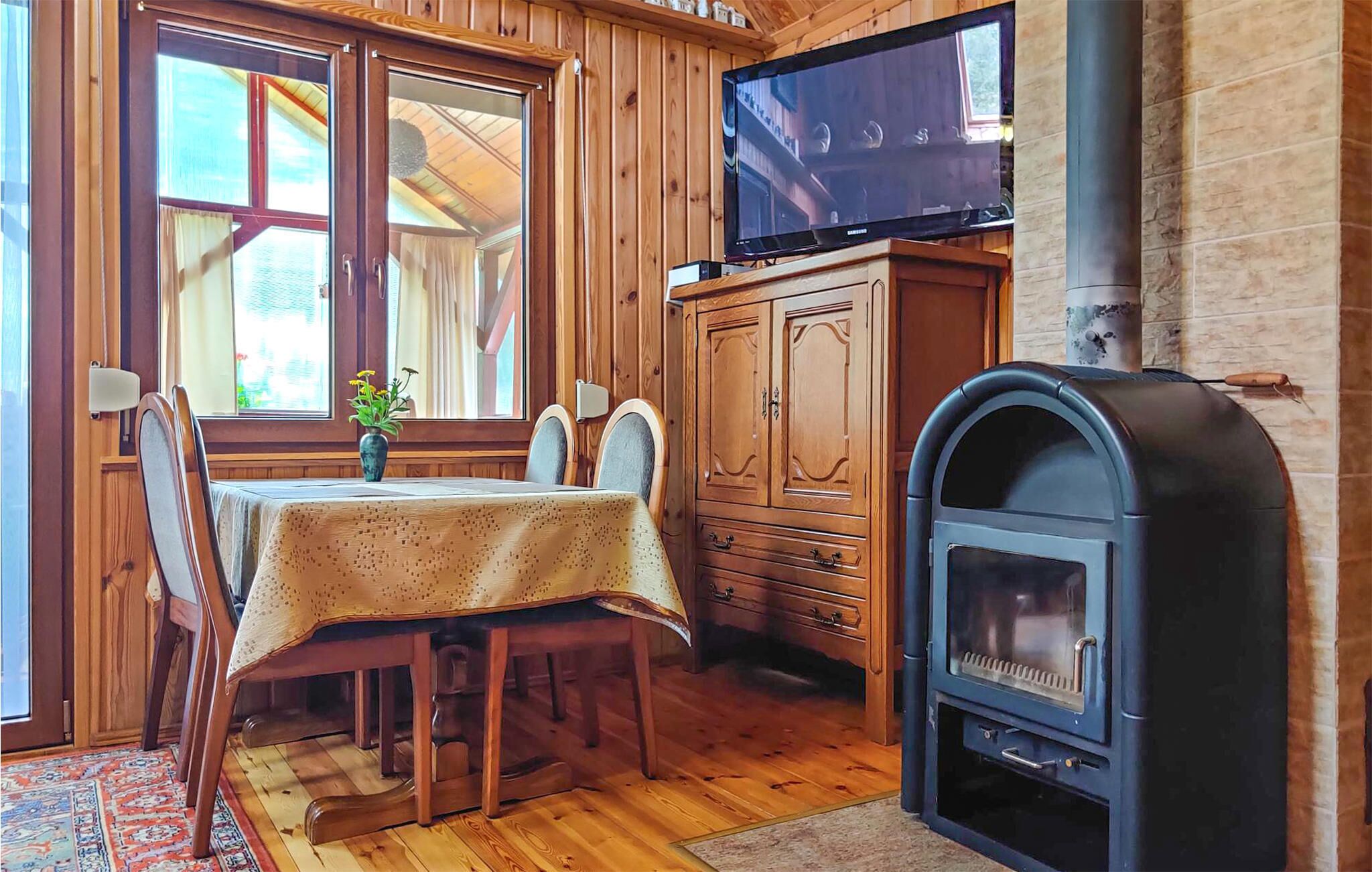 Una habitación acogedora con detalles de madera, un televisor en un mueble, una chimenea y un área de comedor con una mesa y sillas.