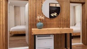 A room with a wooden slat wall, a round mirror, a small table with a vase, and a bed.