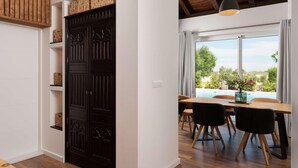 A modern interior with a dark wooden door, a dining area with a pool view, and a hanging light fixture.