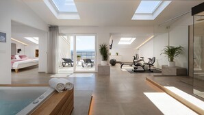 Une chambre d’hôtel moderne avec balcon, salle de sport et vue sur la mer.