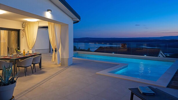 A modern outdoor pool area with a dining setup and a view of the landscape. - Pet friendly home in Smrika with WiFi (Smrika)