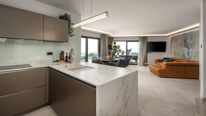 A modern kitchen with a marble island, a dining area with a view, and a living room with a large TV and a sofa. - Pet friendly home in Smrika with WiFi (Smrika)