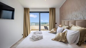 A hotel room with a large bed, a TV mounted on the wall, and a view of the ocean through the window. - Pet friendly home in Smrika with WiFi (Smrika)