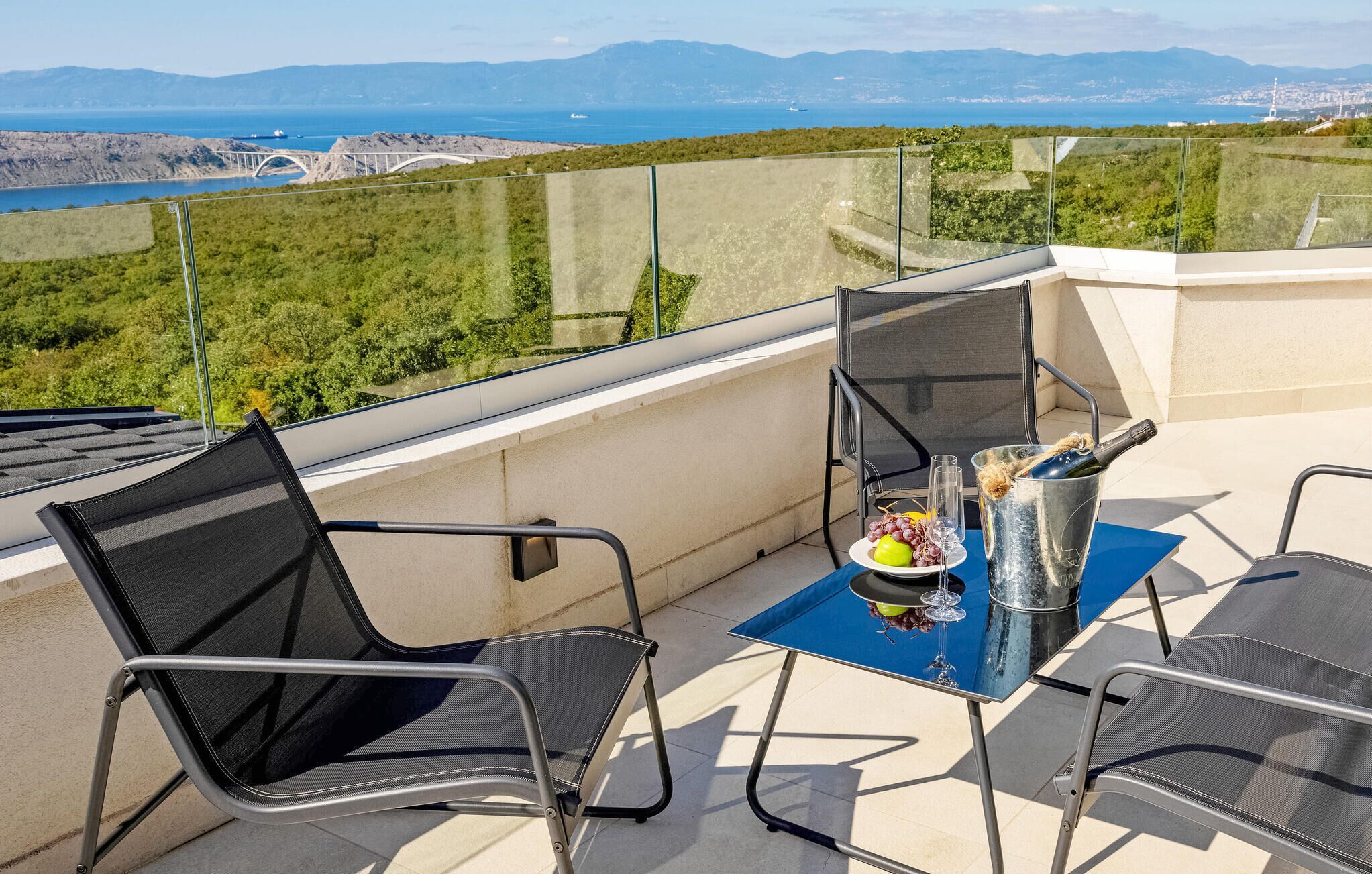 A balcony with a table set for two, a bottle of champagne, and a glass of wine.