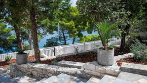 A stone staircase leading to a terrace with potted plants and a view of the sea. - Nice home in Splitska (Splitska)