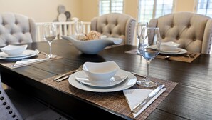 A dining table set with white plates, bowls, and wine glasses, with a bowl of bread on the table. - Peaceful Kierland 2BR Condo | Pool, Spa | Free Parking | Golf Access | Gym Walk to Shops & Dining (Scottsdale)