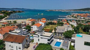 Un pueblo costero con edificios modernos, un puerto deportivo y aguas azul cristalino.