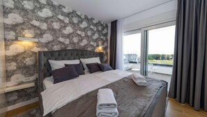 Un dormitorio moderno con una pared de diseño de piedra, un cabecero capitonado y un ventanal con cortinas.