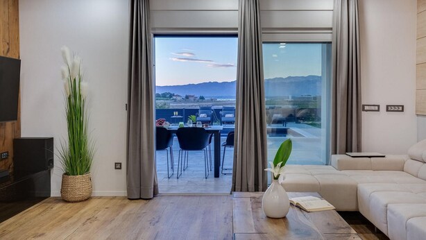 Un salon moderne doté d’une grande fenêtre, d’un canapé, d’une table basse et d’un coin repas avec des chaises et une table.