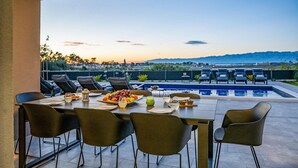 Un espace repas offrant une vue sur une piscine et des montagnes.