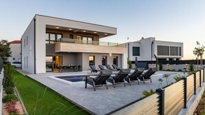 Une maison moderne à deux étages, dotée d’une piscine, d’un espace extérieur aménagé et d’un jardin bien entretenu.