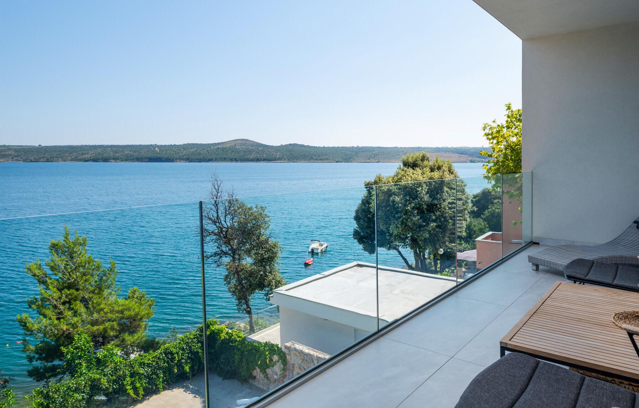 A balcony with a clear view of a lake, a boat, and distant hills.