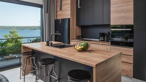 Cozinha moderna com bancada de madeira, banquetas pretas e vista para o lago.