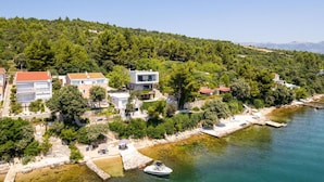 Uma área residencial costeira com casas modernas, um porto de iates e vista clara para o mar.