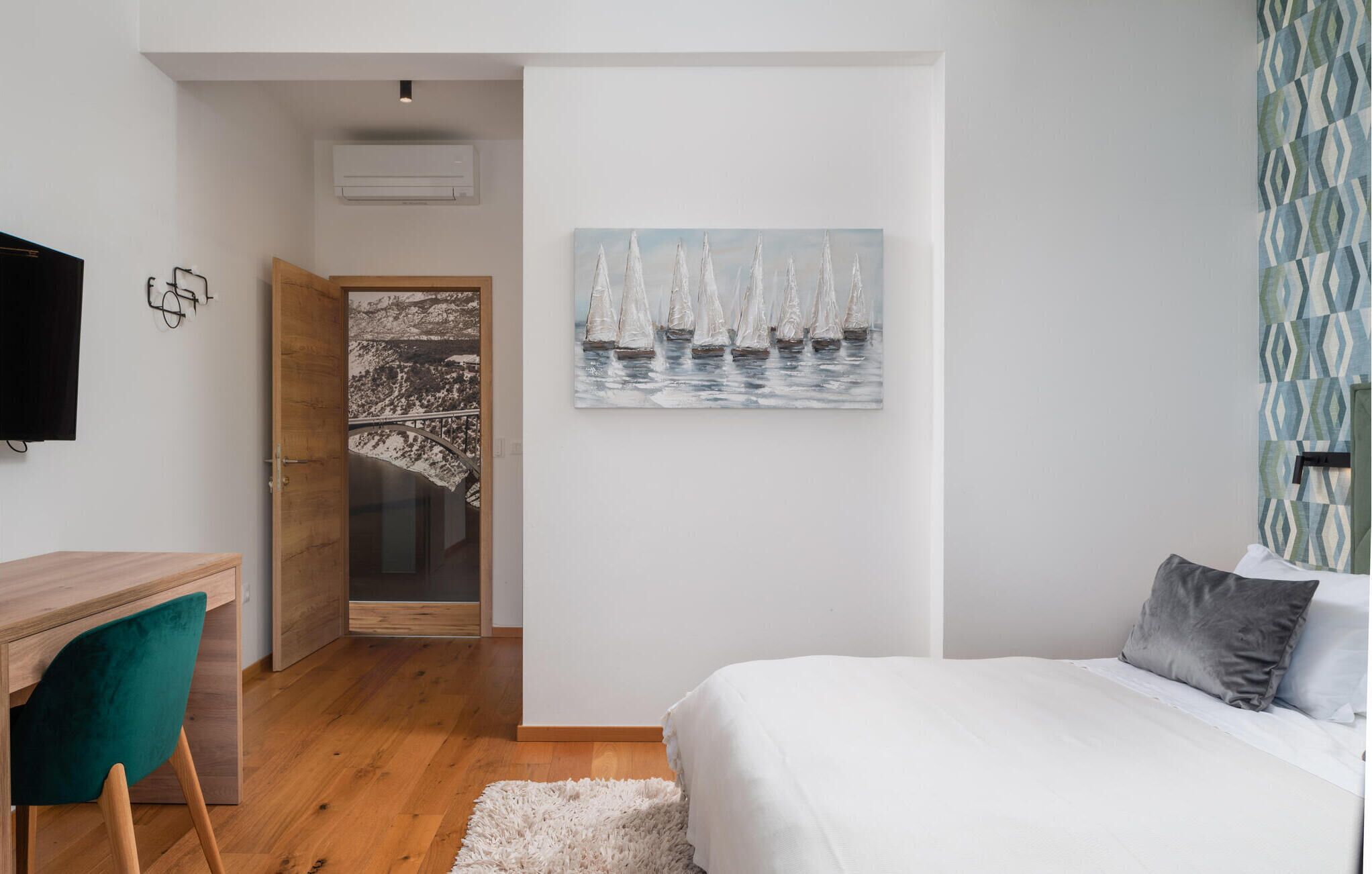 Ein Schlafzimmer mit einem Bett, einem Schreibtisch, einem Stuhl, einem Gemälde und einer Wand mit Muster.