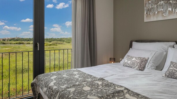 A bedroom with a large bed, a view of a green landscape, and a painting on the wall. - 4 bedroom gorgeous home in Brtonigla (Brtonigla)