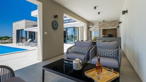 Ein modernes Wohnzimmer mit Blick auf einen Pool, einer Dartscheibe und einem Kamin.