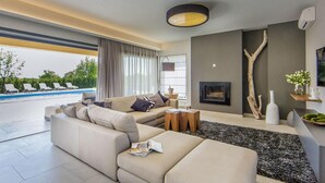 A modern living room with a beige sofa, a coffee table, and a view of a pool. - Pet friendly home in Perini (Perini)