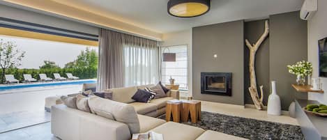 Ein modernes Wohnzimmer mit einem beigefarbenen Sofa, einem Couchtisch und Blick auf einen Pool.