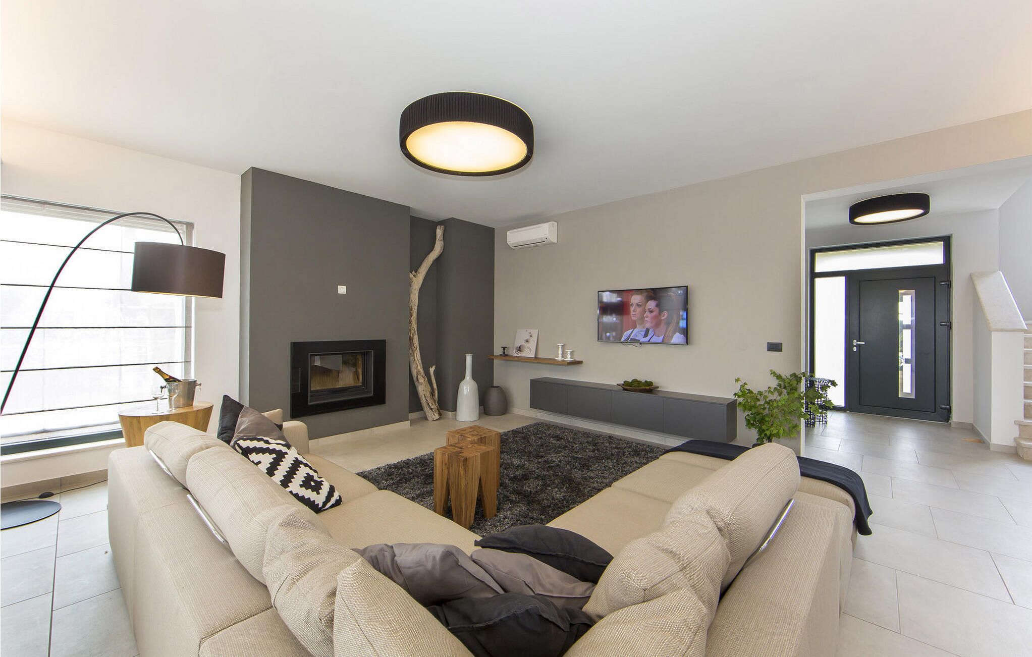 Ein modernes Wohnzimmer mit Sofa, Kamin, Fernseher und einer Treppe, die in einen anderen Raum führt.