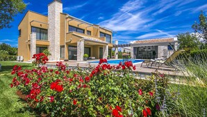 A modern two-story house with a swimming pool, surrounded by lush greenery and red flowers. - Pet friendly home in Perini (Perini)
