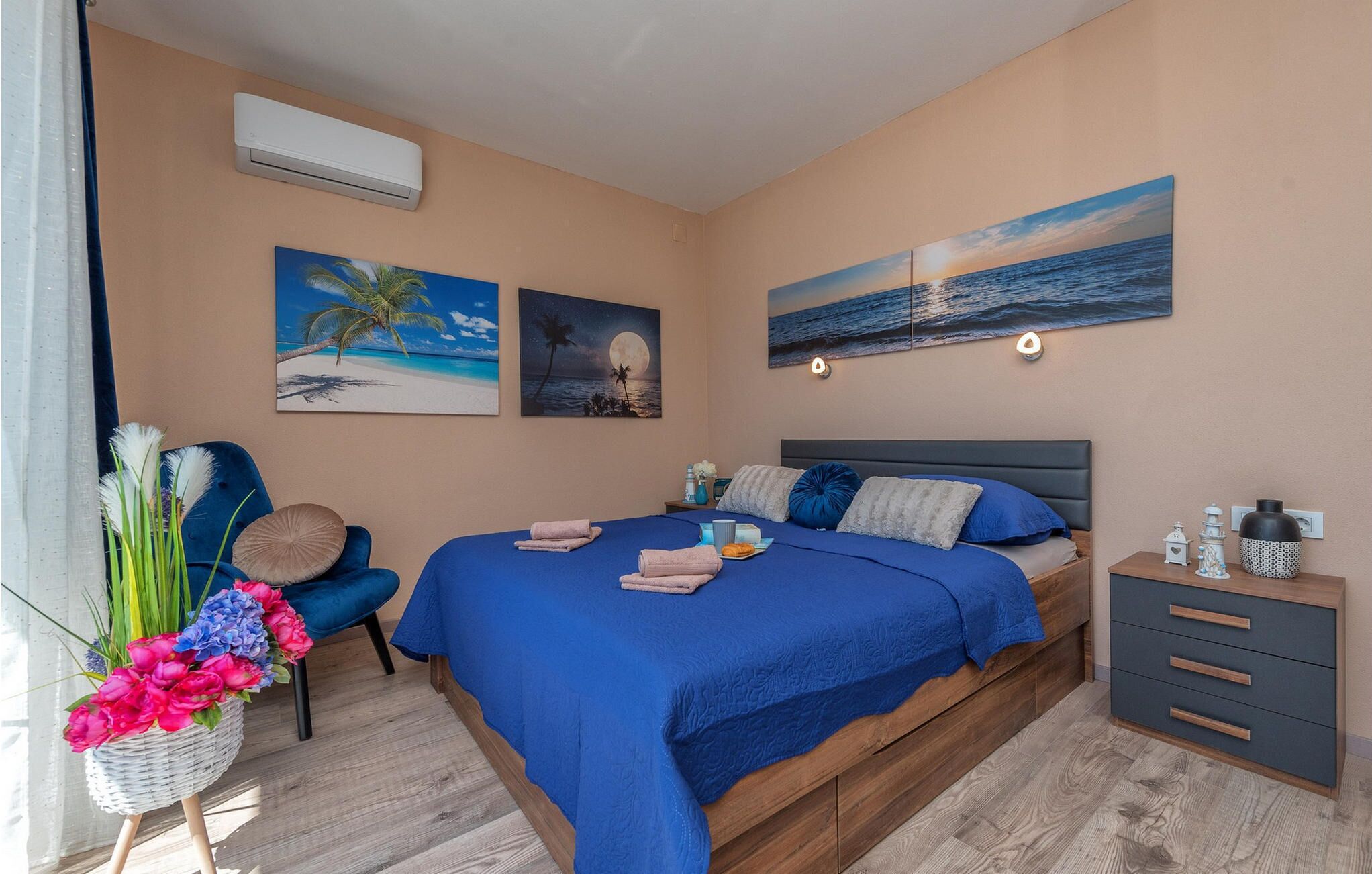 Een slaapkamer met een bed, een stoel, een nachtkastje en wanddecoratie.