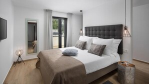 A modern bedroom with a large bed, a flat-screen TV, and a sliding glass door leading to an outdoor area. - Awesome home in Vinez (Vinez)