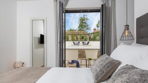 A modern hotel room with a large bed, a balcony with outdoor seating, and a view of the cityscape. - Awesome home in Vinez (Vinez)