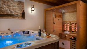 Ein Wellnessraum mit Whirlpool, Holzschränken und einer Steinwand.
