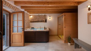 Ein Badezimmer mit Holzboden, einer Steinwand, einer Badewanne und einer Holztür.