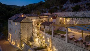 Ein mehrstöckiges Steinhaus mit Außenbestuhlung und einer Treppe, die zu einer Terrasse führt.