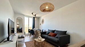 Un salon moderne avec un canapé, une table basse et un téléviseur. Il y a également un coin repas avec des chaises et une table.