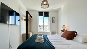 Une chambre à coucher avec un lit, un téléviseur fixé au mur, une fenêtre donnant sur un beau paysage et une lampe de chevet.