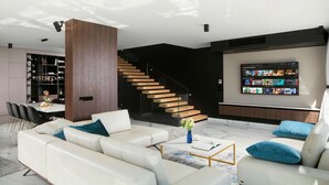 Un salon moderne avec un ensemble de canapés blancs, une table basse et un escalier menant à un autre niveau.