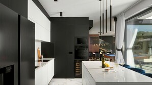 Une cuisine moderne dotée d’un îlot central, d’appareils électroménagers intégrés et offrant une vue sur l’extérieur.