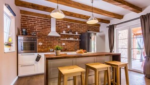 A kitchen with a brick wall, wooden beams, stainless steel appliances, and a large window. - 3 bedroom lovely home in Krk (Krk)