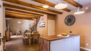 A kitchen with a wooden island, a clock on the wall, and a staircase leading to another room. - 3 bedroom lovely home in Krk (Krk)
