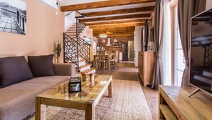 A cozy living room with a sofa, coffee table, and TV. A staircase leads to a dining area with a kitchen in the background. - 3 bedroom lovely home in Krk (Krk)