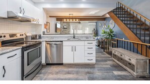 A modern kitchen with white cabinetry, stainless steel appliances, and a herringbone-patterned floor. - 4 Seasons Wisp - Ski In/Ski Out Townhome with Lake Access, Hot Tub  (McHenry)