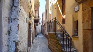 Un stretto vicolo con un muro di pietra su un lato e un edificio giallo sull'altro. Una ringhiera metallica si trova sulla destra.