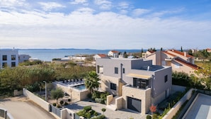 A modern villa with a swimming pool, stone walls, and a view of the sea. - Beautiful home in Privlaka with sauna (Privlaka)