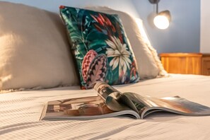 A bed with a pillow, a magazine, and a lamp.