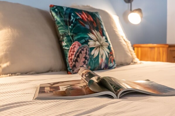 A bed with a pillow, a magazine, and a lamp.