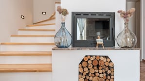 A modern interior with a fireplace, wooden staircase, and a small easel with artwork. - Villa Mariva (Carro d'oro) (Vrana)