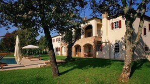Een villa met een zwembad, buitenmeubilair en een verzorgd gazon.