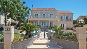 A two-story building with a balcony, a pool, and a gate with the number 582.