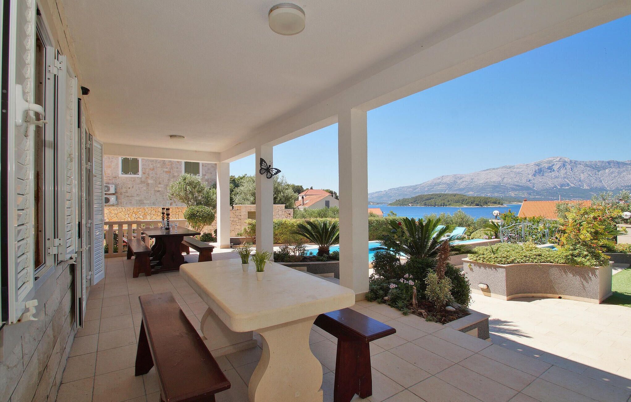 Un espace extérieur abrité, doté d’une table et de bancs, d’une piscine, et offrant une vue sur la mer et les montagnes.