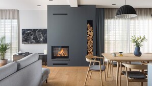 Un salon moderne avec une cheminée, un coin repas et un canapé.