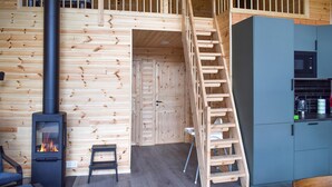 L’intérieur d’une cabane en bois comprend une cheminée, un coin cuisine et une mezzanine.